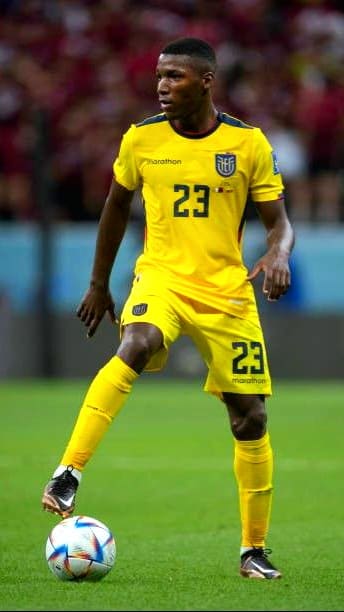 A soccer player in a yellow Ecuador national team uniform with number 23 controls the ball on a field during a match, as fans around the world watch the action live through Nordic IPTV.